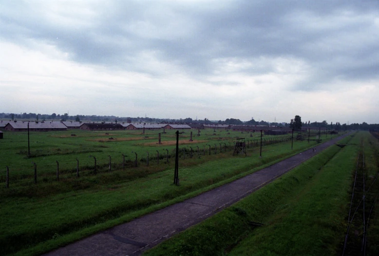 a very long road near the fields in an overcast sky