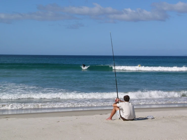 a man fishing on the beach in front of the ocean