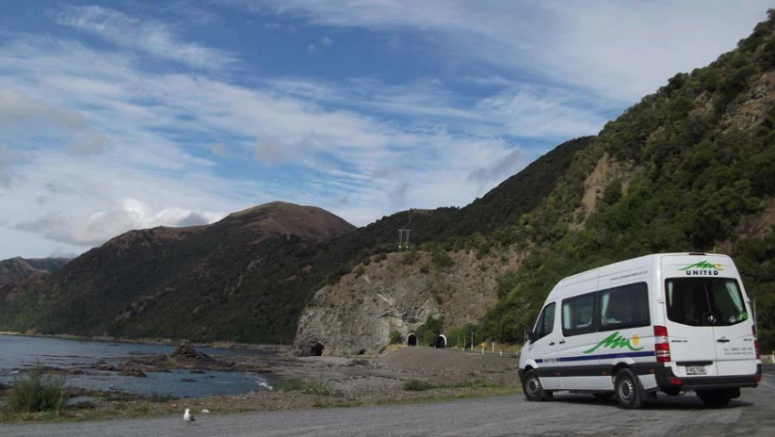 a camper van parked on a road near a mountain side