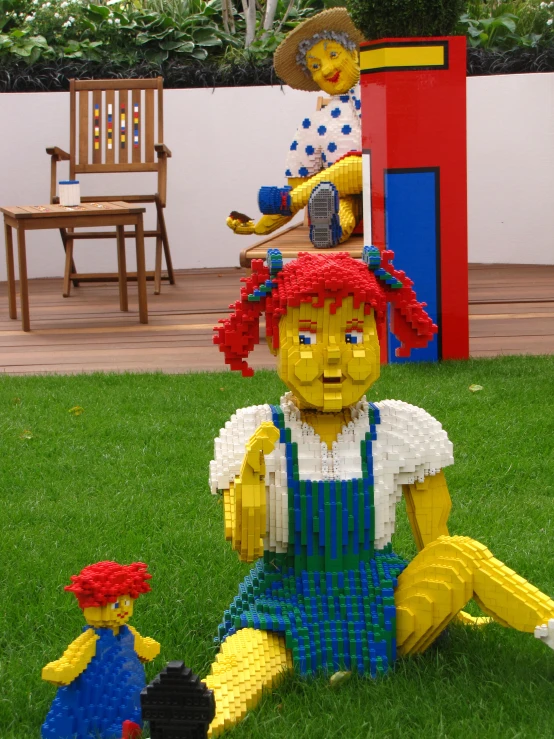 a lego woman and a toy sitting on the grass