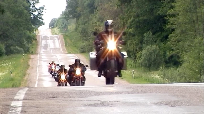 some bikers are riding down the road with bright headlights