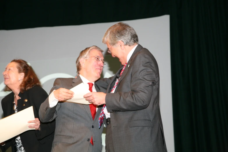 three people are congratulating one another after a speech