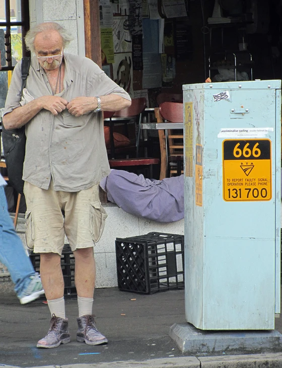 man standing in front of a parking meter, with his hands folded out