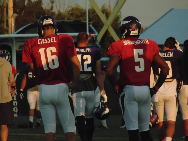 two football players with helmets on stand in a line