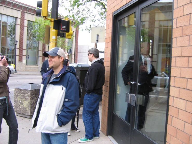 people are standing on the sidewalk near the building while taking pographs