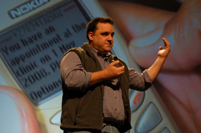 a man giving a speech in front of a screen