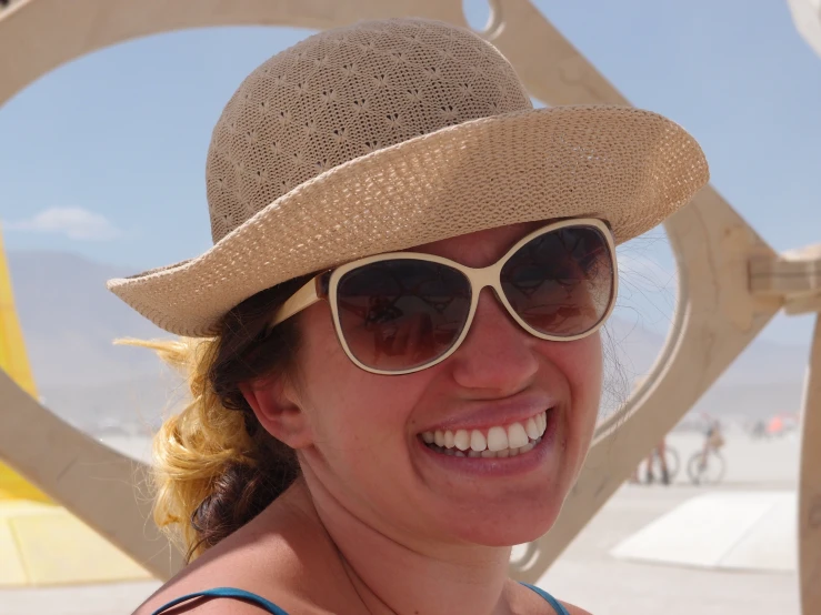 a woman wearing sunglasses and a hat smiles