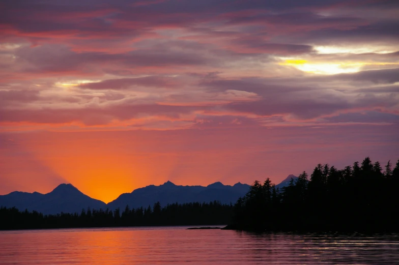 a mountain range looms above the clouds at sunset