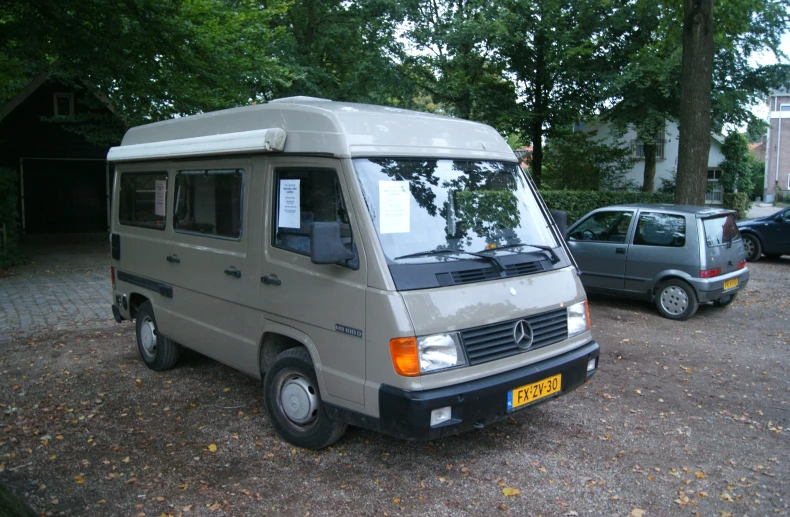 a small vehicle parked next to a car in front of some houses