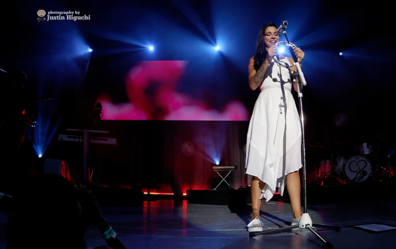 a woman on stage holding a microphone on a microphone stand