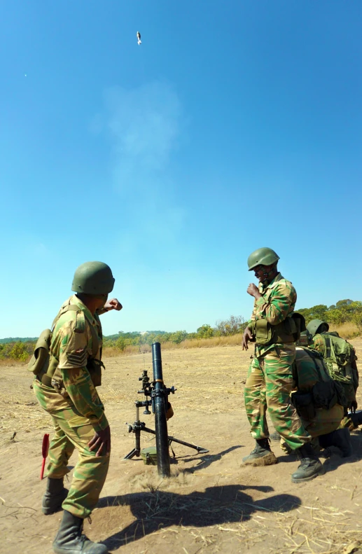 four soldiers in uniform standing around and aiming