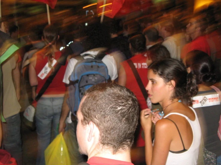 many people stand and look at soing and one person holds onto a backpack