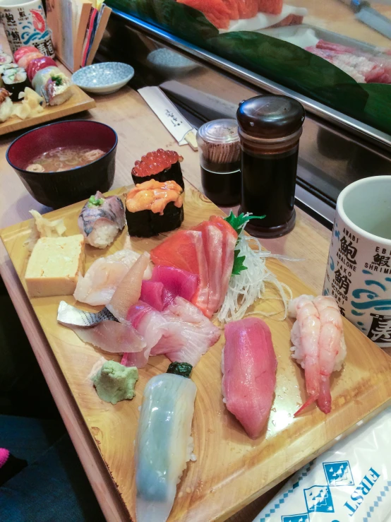 sushi on a wood serving tray with bowls of other foods