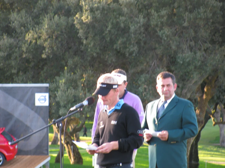 three people standing at a podium holding paper in their hands