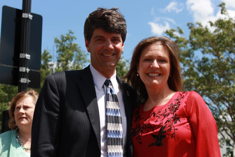 a man in a suit stands with his arm around a woman's shoulder