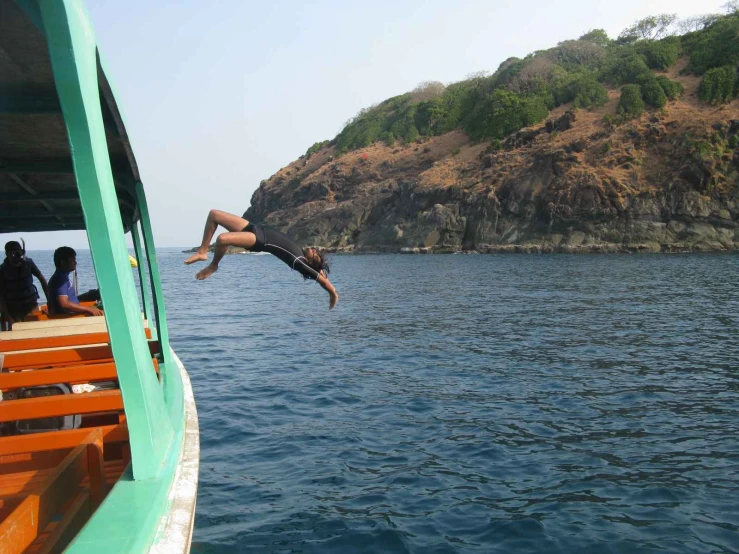 a young man dives off a boat into the water as several others look on