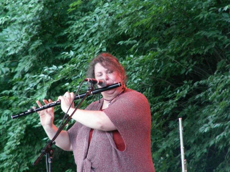 a man singing into the microphone with trees in the background