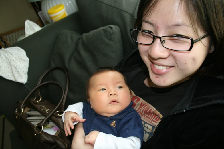 a woman holding a baby next to a purse