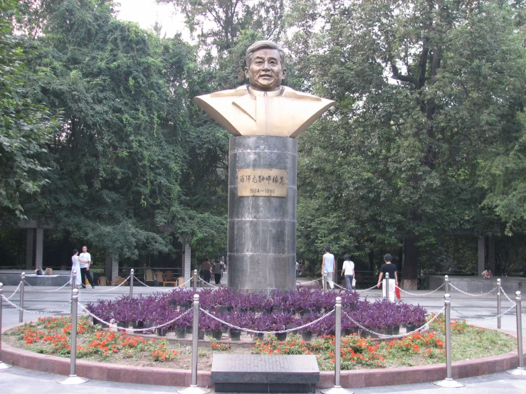 a sculpture with purple flowers and people around it