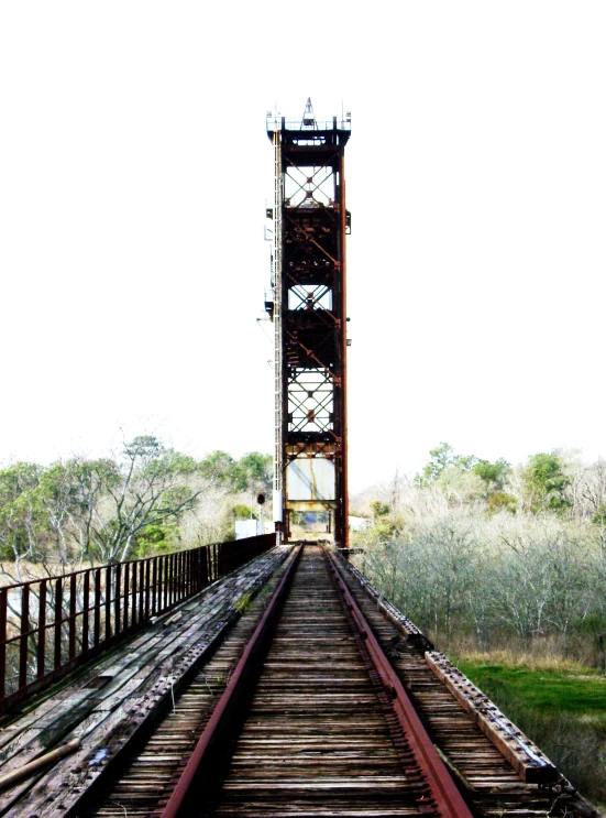 an old brown railroad bridge crossing over the tracks