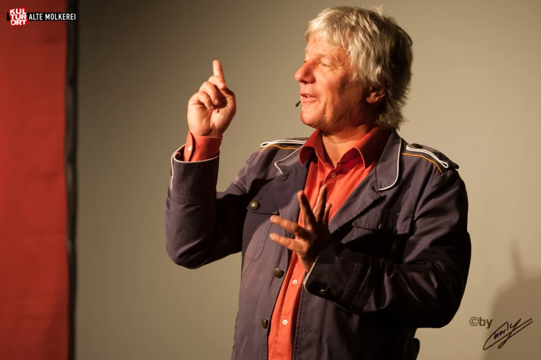 a man wearing an orange shirt pointing to soing