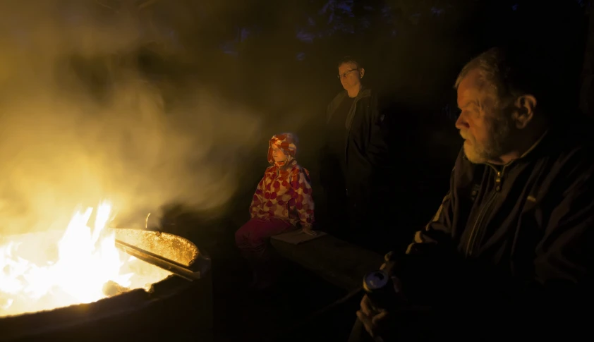 a woman sitting next to a fire in the street