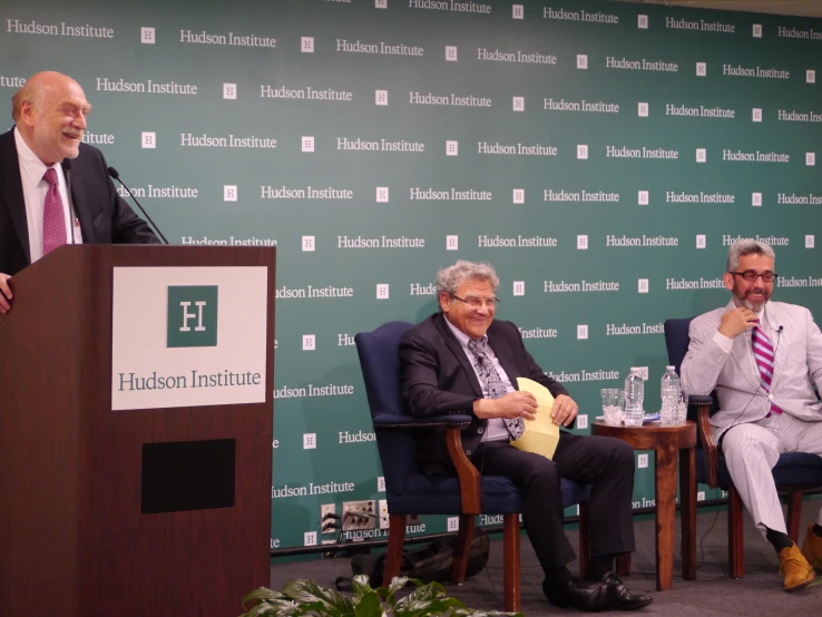 two men sitting in chairs on the stage talking