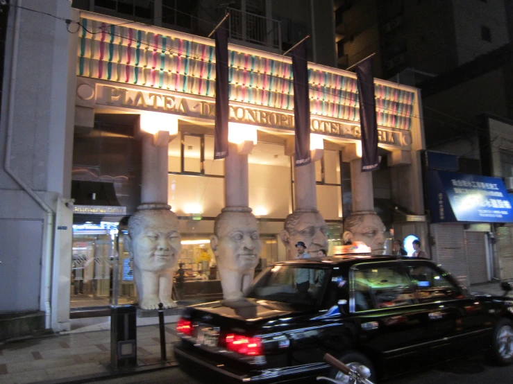 a car on the street in front of some large, carved heads