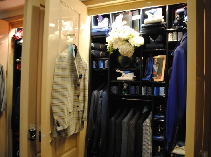 a suit closet with clothes on racks, and a shelf in the closet