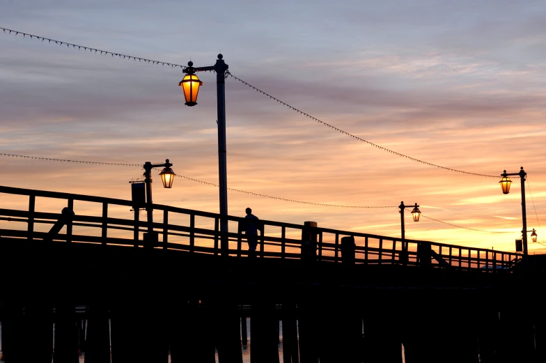 a bench at the end of a bridge with street lights on