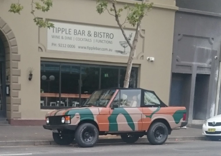 the orange and green vehicle is parked next to the curb