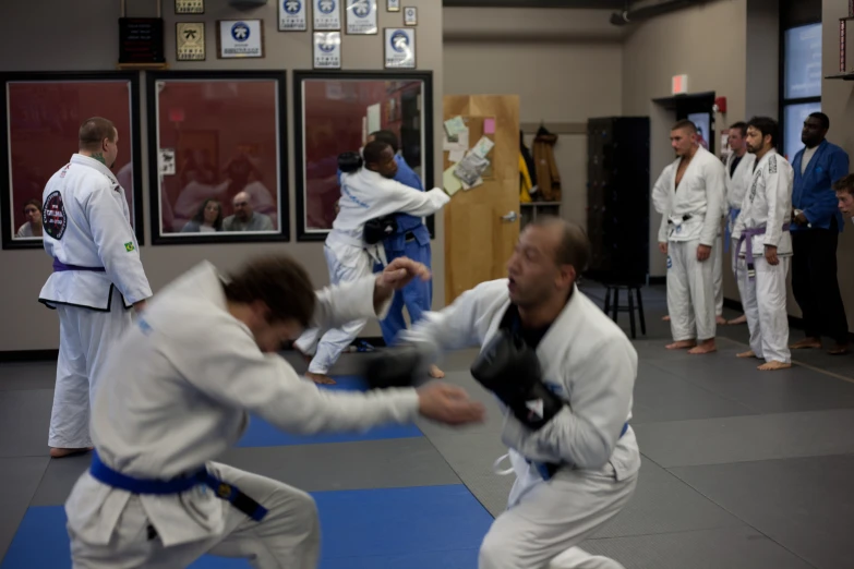 people in white kimonos in a karate class with others in blue belted suits