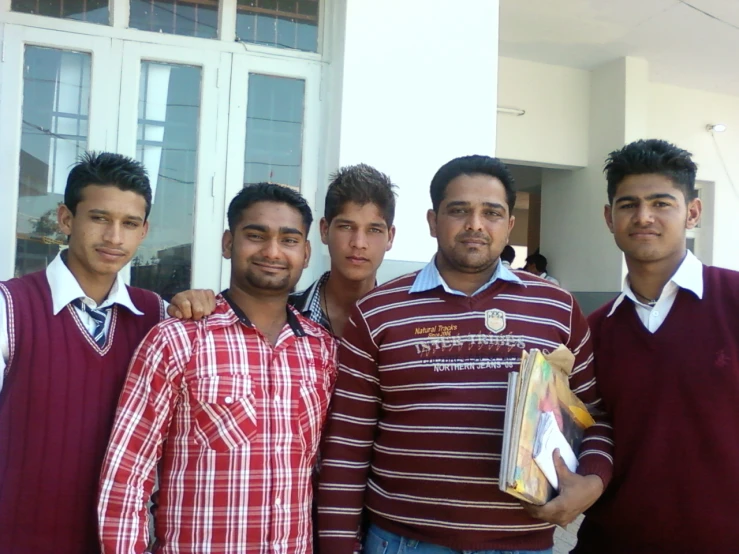 six men wearing sweaters standing together and smiling