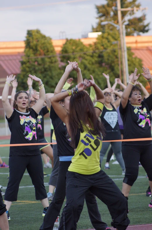 a group of women are stretching out with their arms in the air