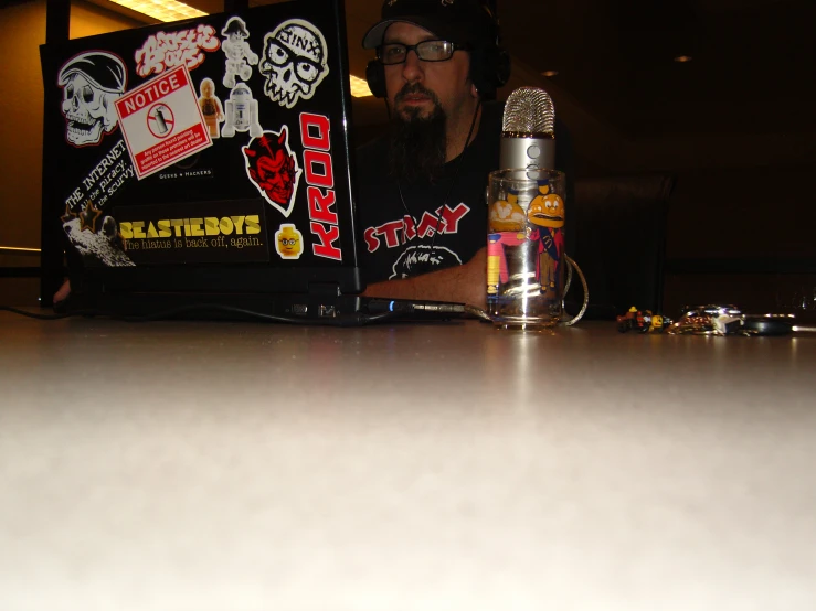 a bearded man using a laptop with stickers on it