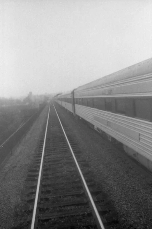 a white train traveling down railroad tracks with fog