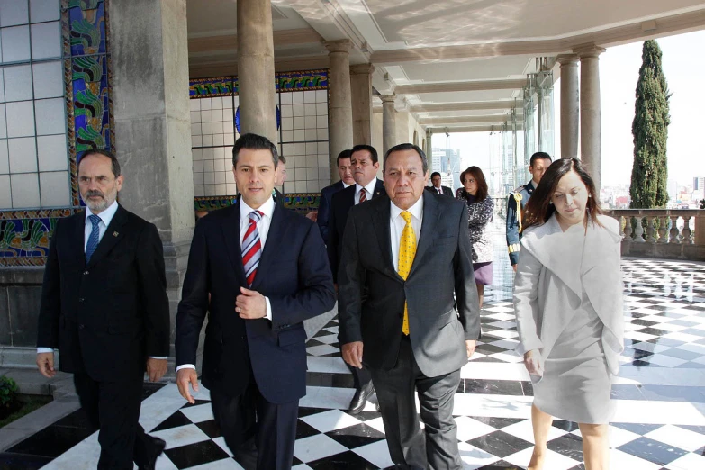 two men walking past another man in a suit