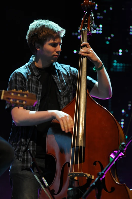 a young man holding onto a large musical instrument