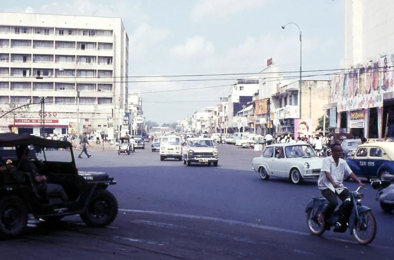 a man rides a motorcycle and a car on a busy city street