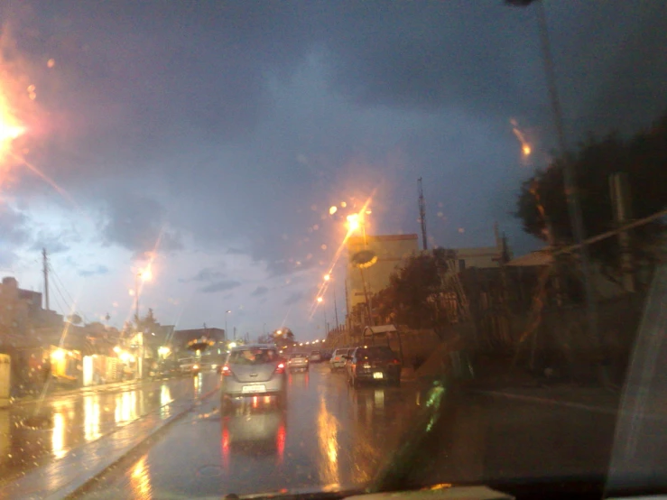 a view from inside a car at night with cars parked on the street