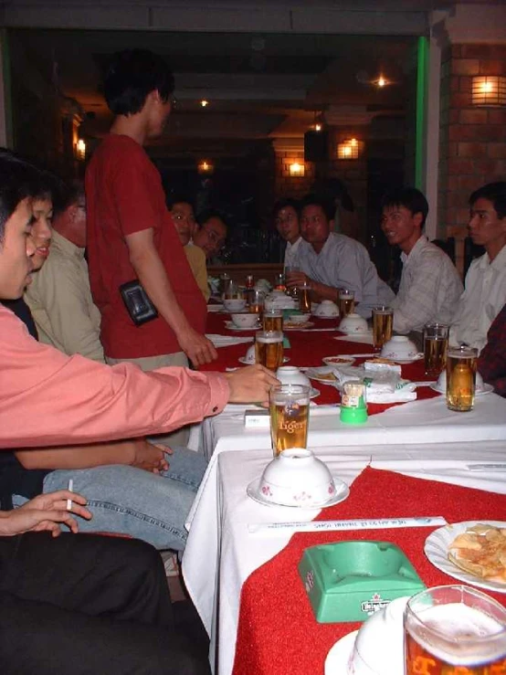 several people sitting at a long table with a plate