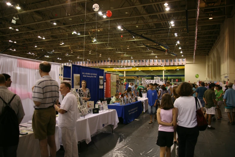 a crowd of people walk through an indoor market area