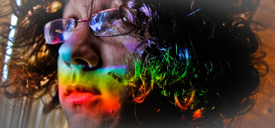 a man with his nose to the side and the rainbow painted face