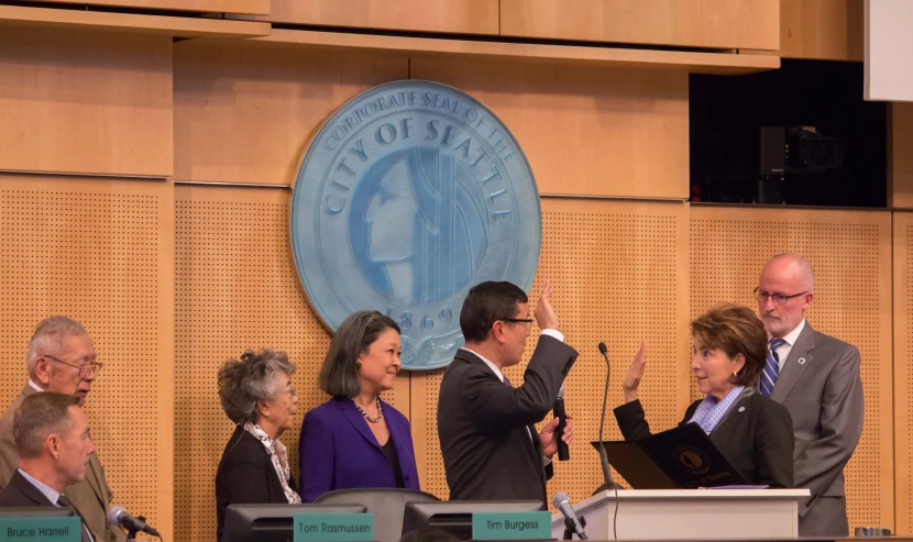 several people sitting at tables in front of a microphone