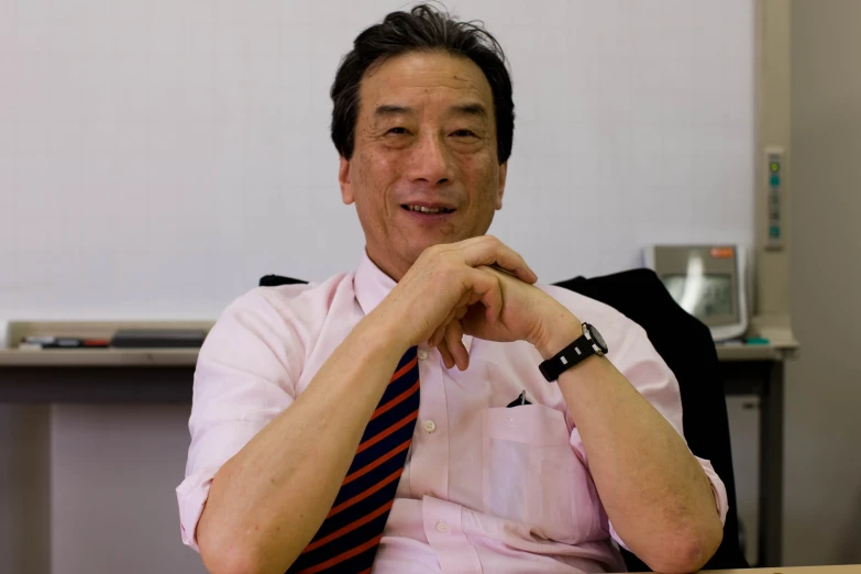 a man with a tie on sitting in an office