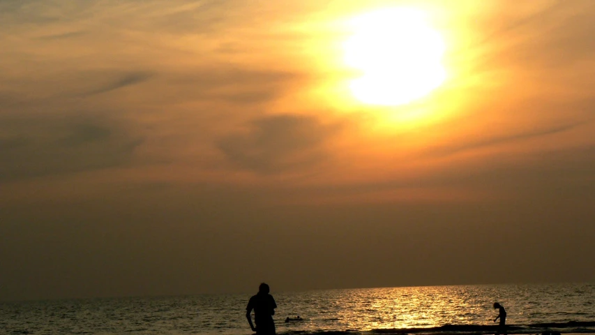 three people on a beach with a kite flying in the air