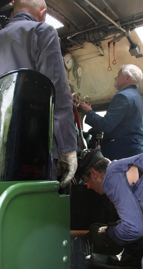 two men are repairing a vehicle while another person stands near