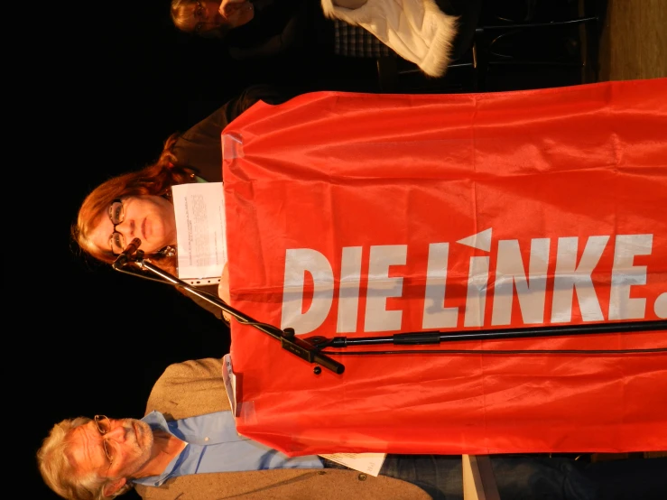 a man and woman stand under an advertit banner