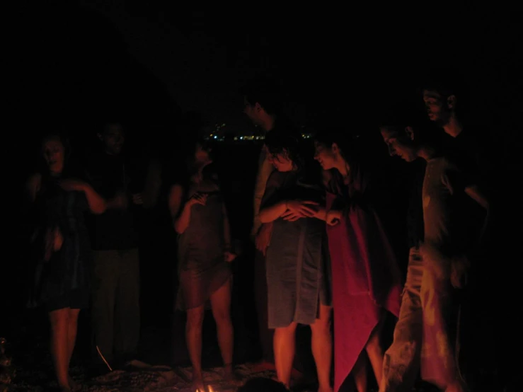 a group of people stand together around a camp fire