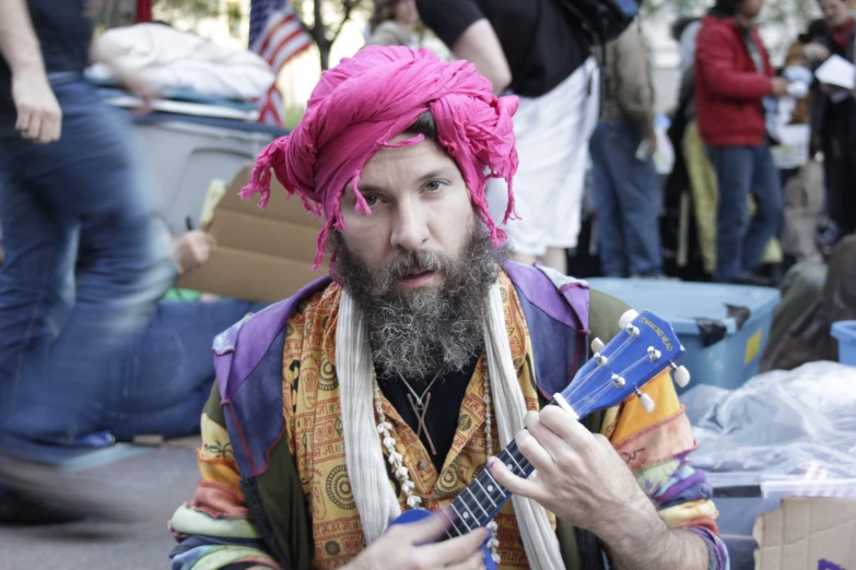 a man wearing a colorful head piece and playing a guitar